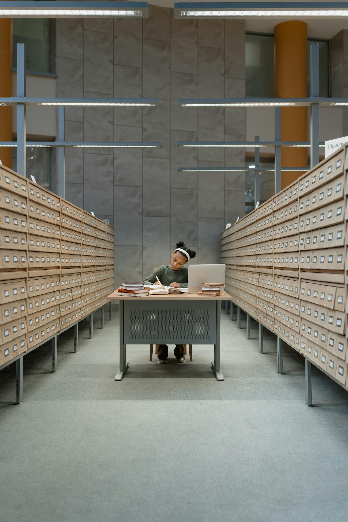 A girl studies among card catalogs in a library, focused on learning and research.