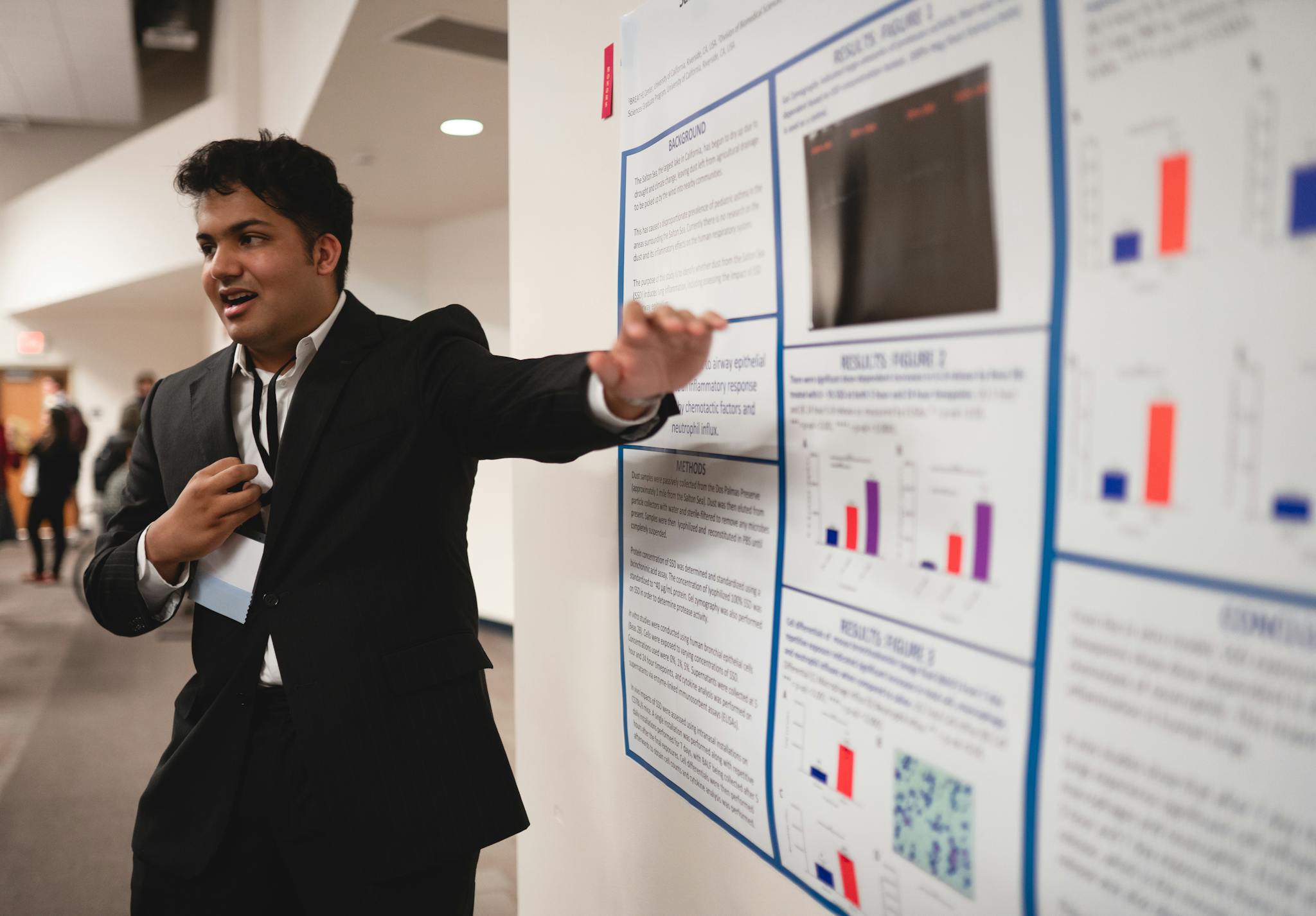 Confident young man in suit presenting research findings on a poster at a conference.